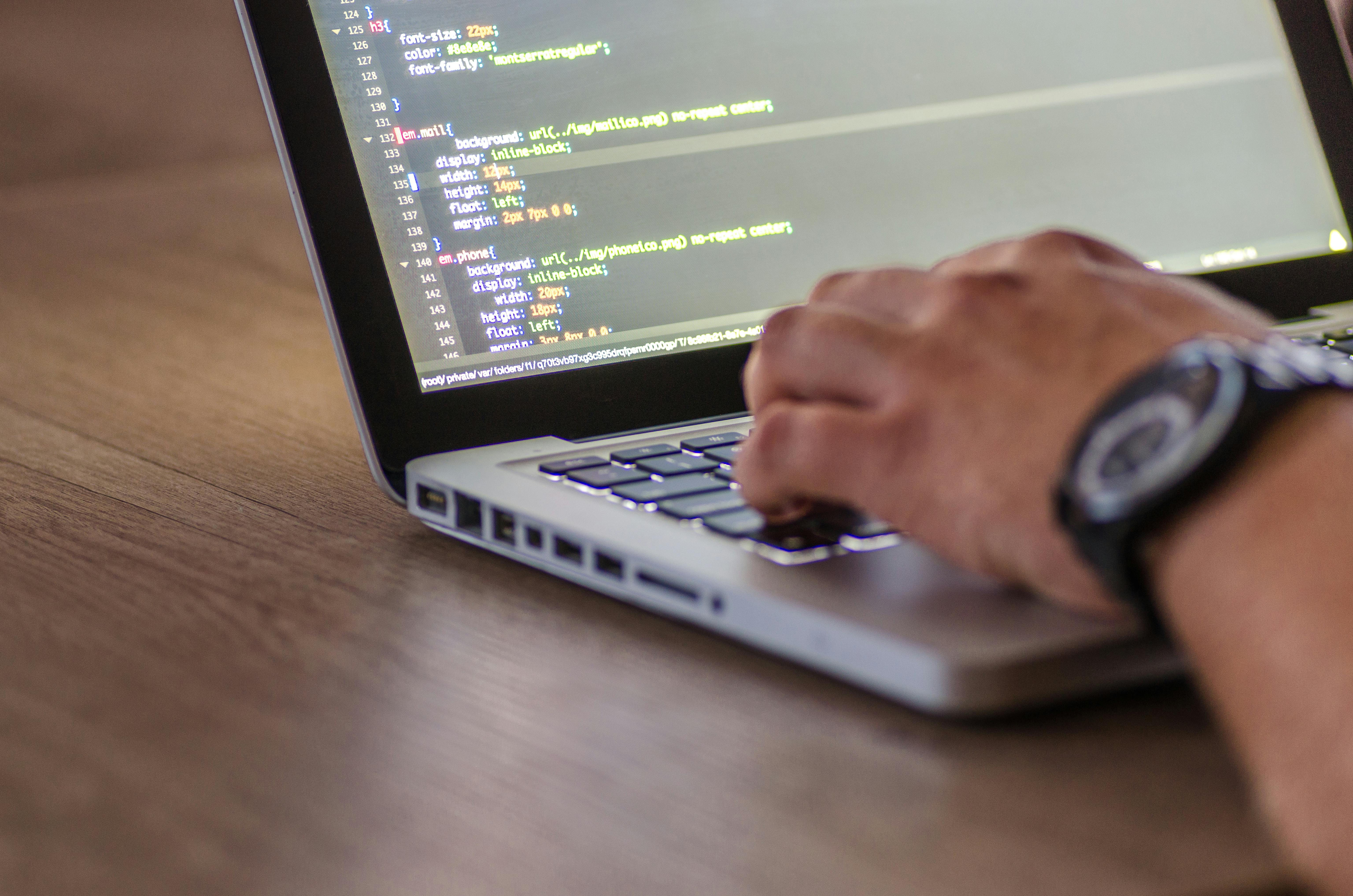 hands typing on a laptop - benefits of custom software development concept